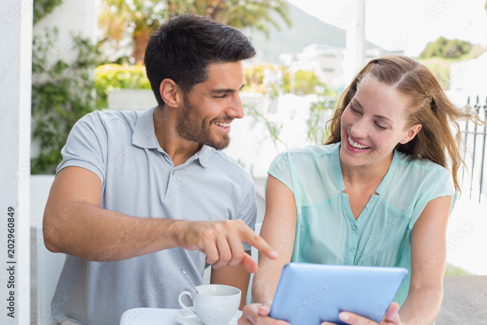 Smiling couple with coffee cup using digital tablet at café Smiling couple with coffee cup using digital tablet at café