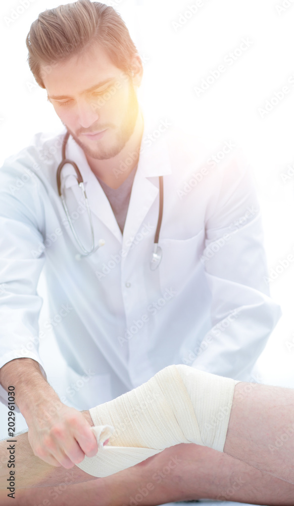 doctor looking at the bandage on the patient's leg doctor looking at the bandage on the patient's leg