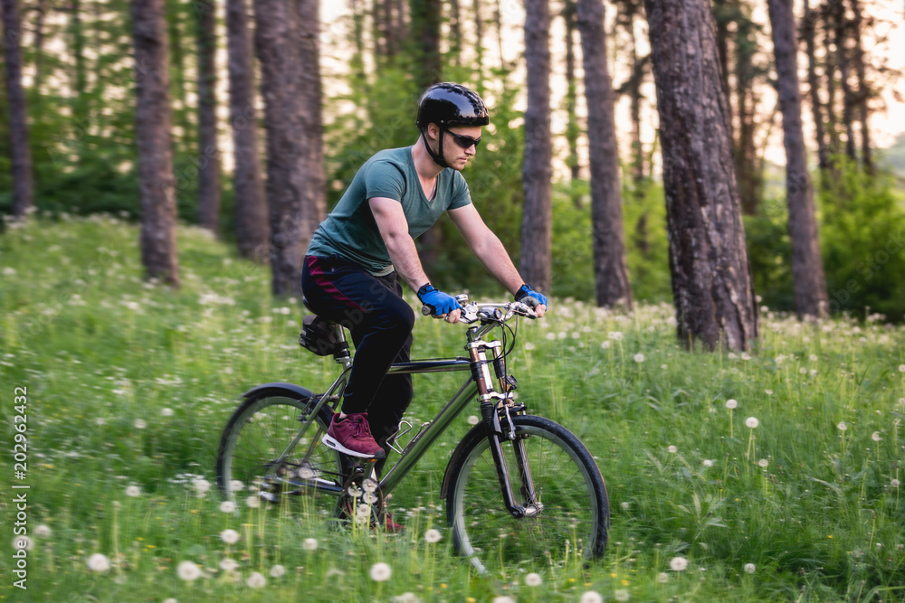Young man drive his bike in nature in deep grass