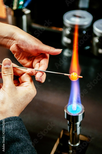 Shaping glass bead in fire, Glass Making Artisan in His Workshop