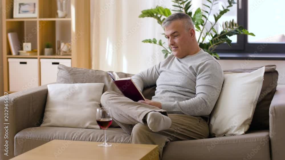 leisure and people concept - happy smiling man drinking red wine and reading book at home leisure and people concept - happy smiling man drinking red wine and reading book at home