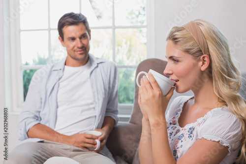 Relaxed couple with coffee cups sitting in living room