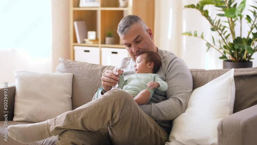 family, fatherhood and people concept - happy father with little baby boy sitting on sofa at home family, fatherhood and people concept - happy father with little baby boy sitting on sofa at home