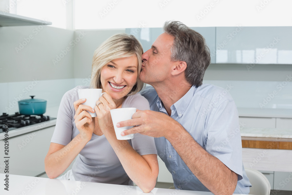 Loving couple with coffee cups in kitchen Loving couple with coffee cups in kitchen