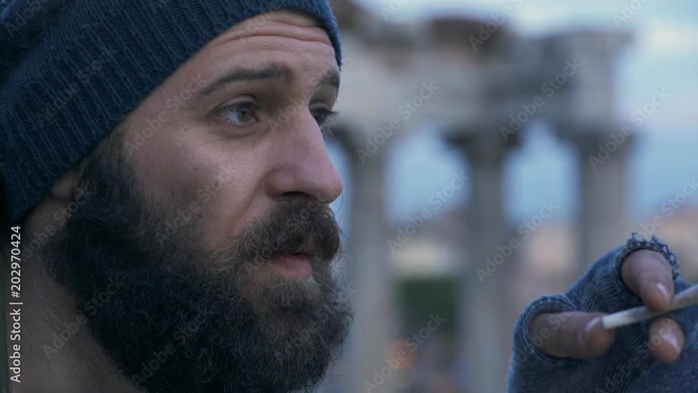 Thoughtful dirty homeless lighting cigarette- outdoor Thoughtful dirty homeless lighting cigarette- outdoor