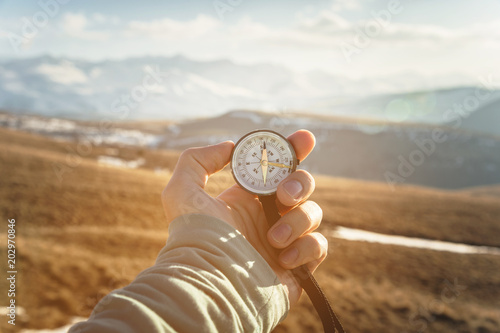 Canvas Print a man's hand holds a hand-held compass against the backdrop of mountains and hills at sunset