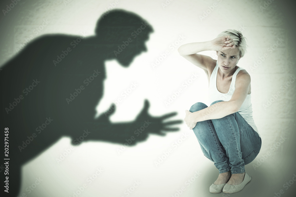 Φωτογραφία Crouching sad woman holding her hand against silhouette of shouting man