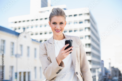 Happy attractive businesswoman sending a text message