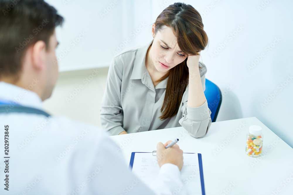 Φωτογραφία Portrait of frowning young woman listening to doctor while sitting at desk in cl