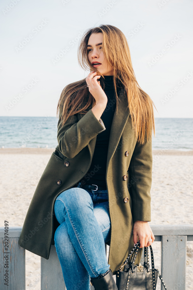 Beautiful young woman with long hair in a green coat