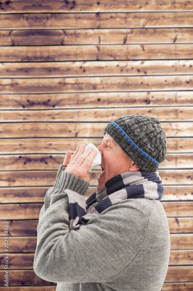 Sick mature man blowing his nose against wooden planks background Sick mature man blowing his nose against wooden planks background