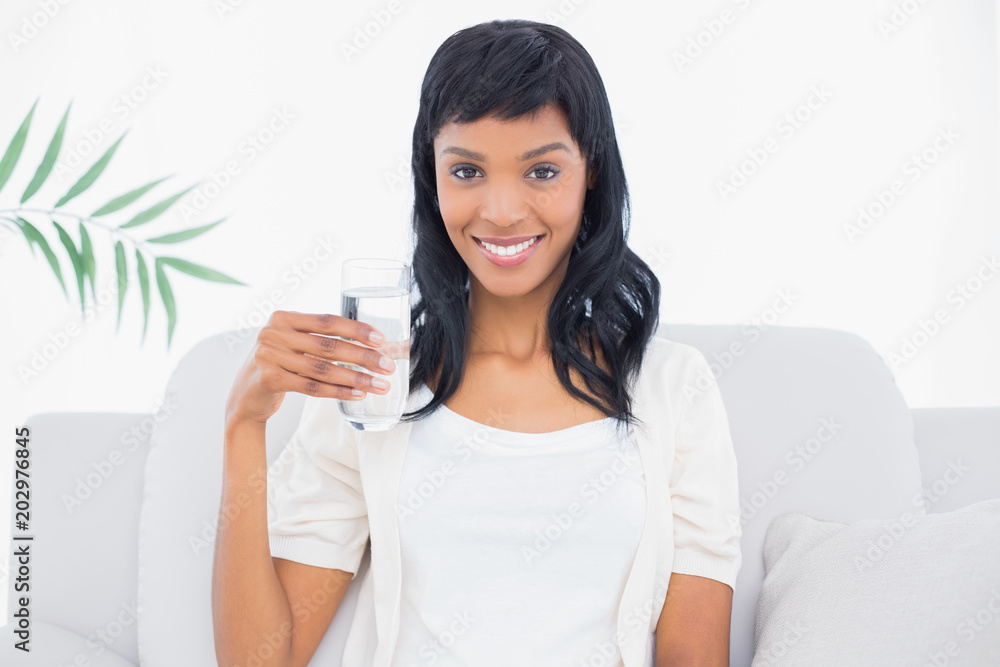 Content black haired woman in white clothes holding a glass of water Content black haired woman in white clothes holding a glass of water
