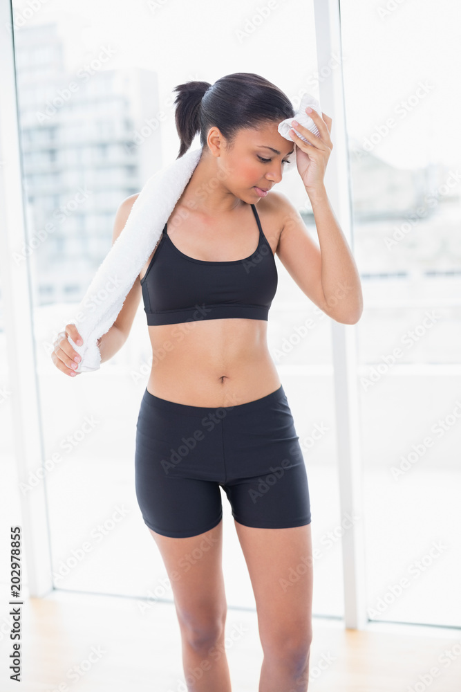 Exhausted dark haired model in sportswear drying herself with a towel Exhausted dark haired model in sportswear drying herself with a towel