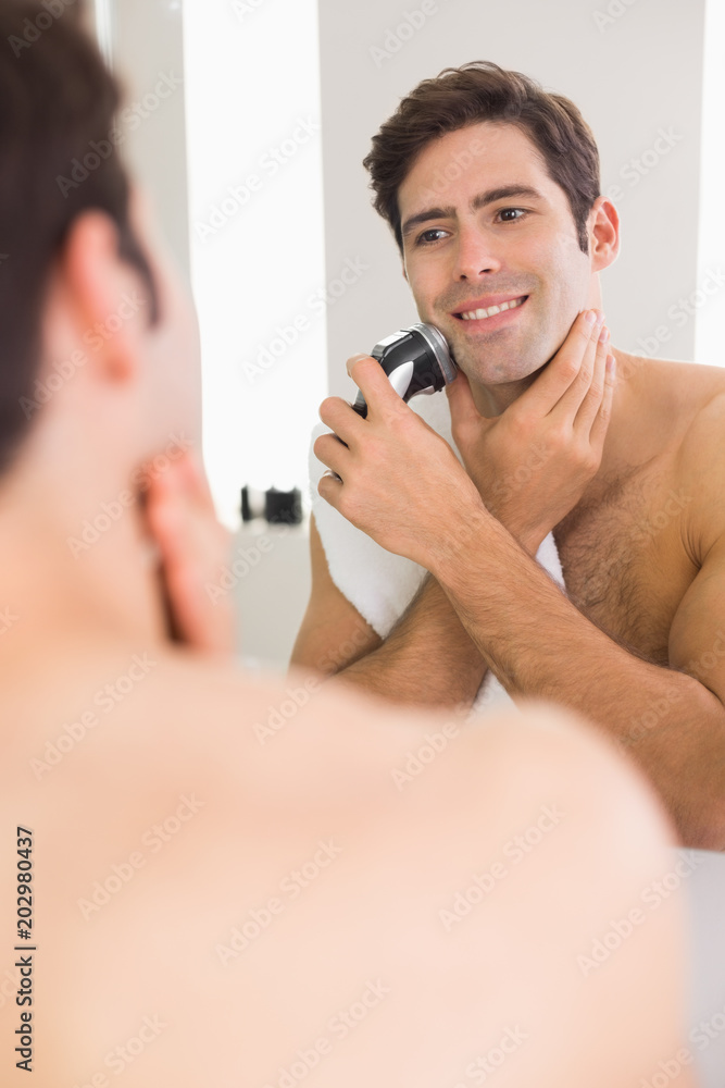 Reflection of shirtless man shaving with electric razor Reflection of shirtless man shaving with electric razor