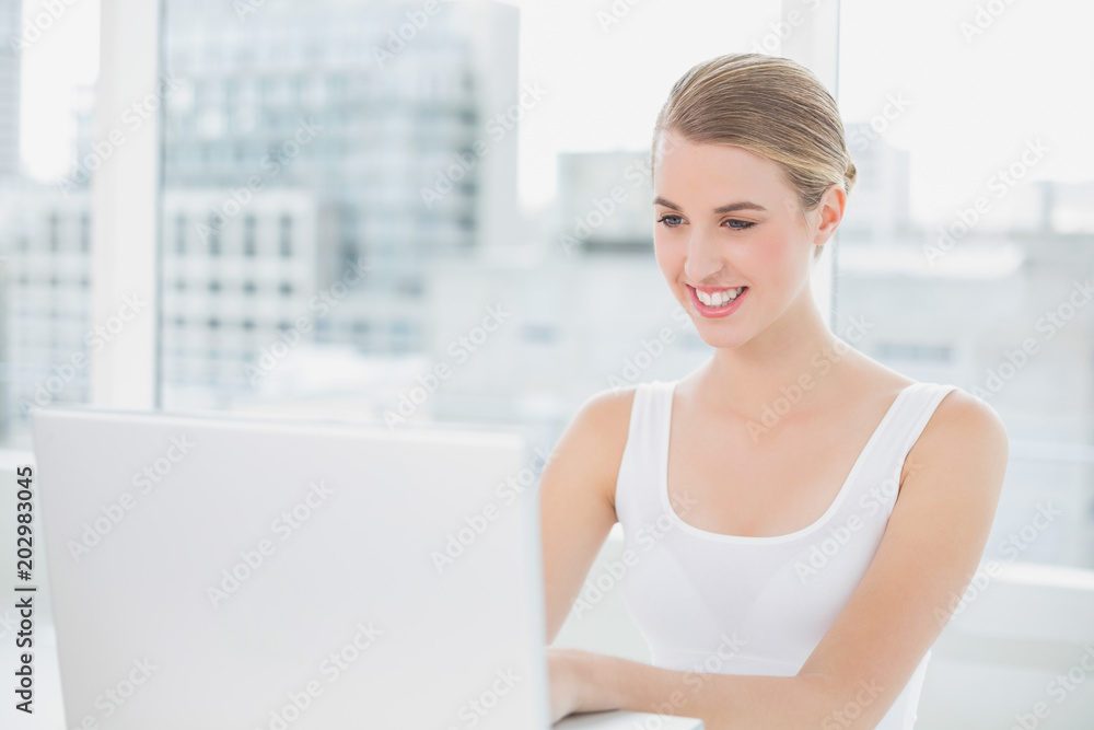 Smiling blonde using her laptop Smiling blonde using her laptop