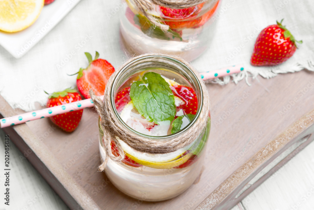 Mineral water with fresh strawberries, lemon and mint in jar on a white wooden background, copy space Mineral water with fresh strawberries, lemon and mint in jar on a white wooden background, copy space