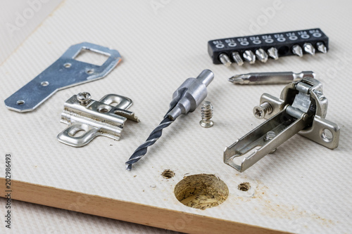 Assembly of hinges in a carpentry workshop. Joinery accessories in a carpentry workshop on a wooden table.