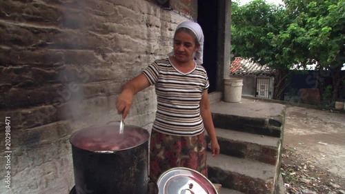 Salvadoran woman stirring bean soup in kettle over outdoor fire photo