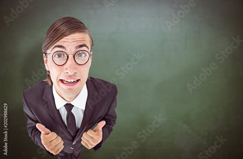 Geeky businessman looking at camera thumbs up  against green chalkboard