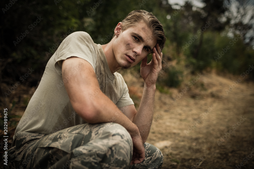 Tired soldier with hand on head sitting in boot camp Tired soldier with hand on head sitting in boot camp