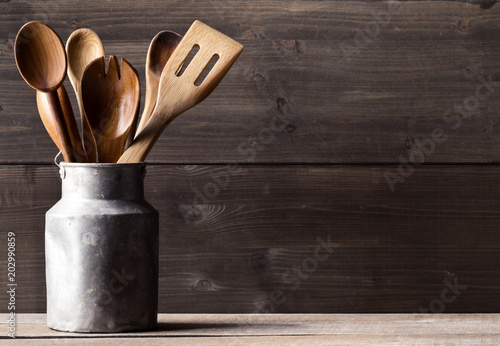 Wooden kitchen cooking tools with spoons and spatula in front of rustic wooden board background