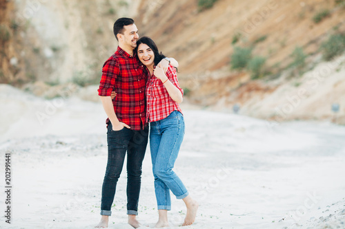 Young couple in plaid shirts stand embrace at sand canyon or quarry. Outdoors. Copy space