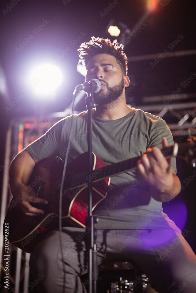 Male musician with eyes closed singing at nightclub Male musician with eyes closed singing at nightclub