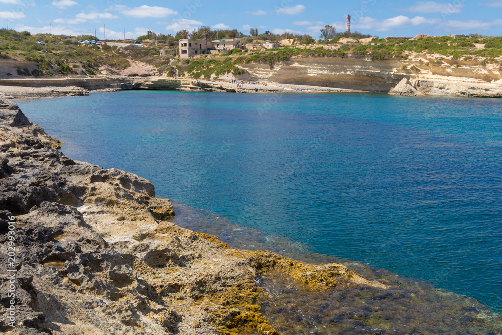 Limestone rock shelves, and crystal clear blue waters of Mediterranean sea at Il Kalanka Beach, Delimara point, Delimara, Malta