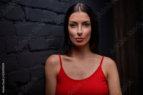 Young woman in red smiling against black wall