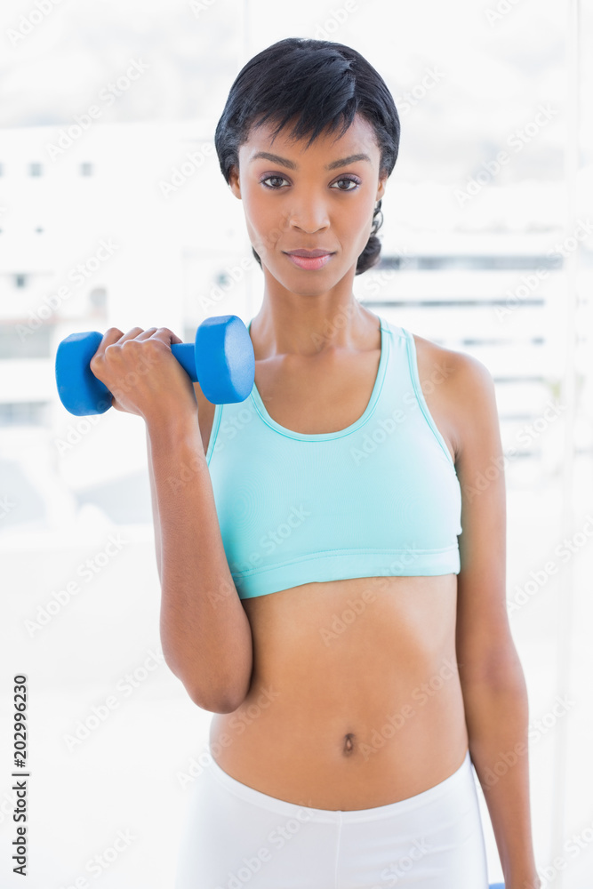 Stern black haired woman holding a dumbbell