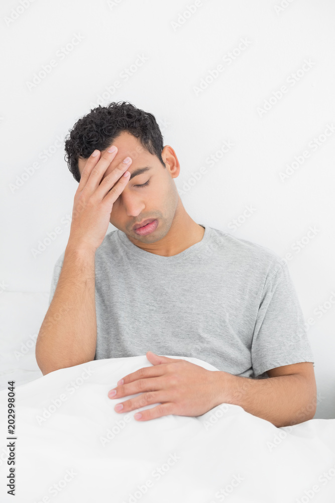 Man suffering from headache in bed Man suffering from headache in bed