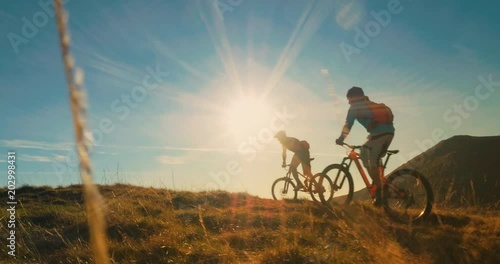 Two mountain bikers riding their bikes to the top in amazing sunlight.