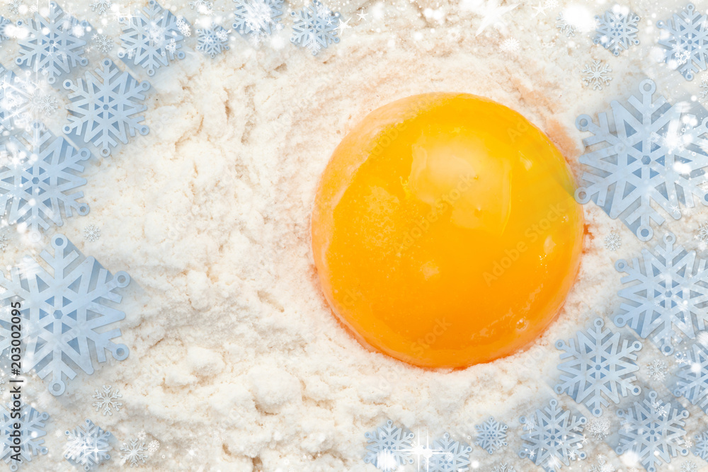 Composite image of snow flakes against egg yolk on the flour
