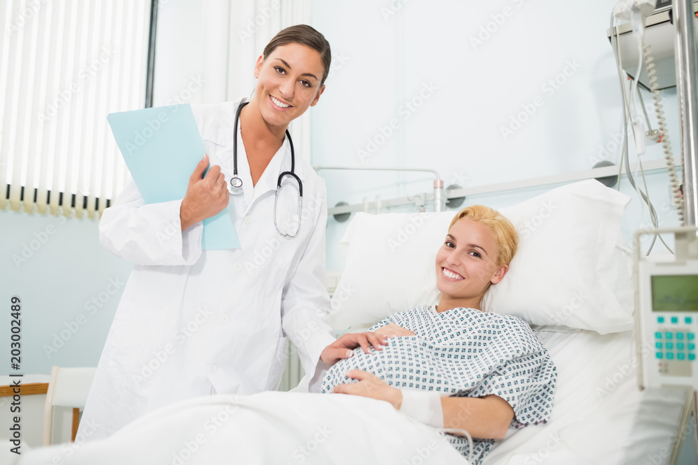 Female obstetrician talking to a smiling pregnant woman Female obstetrician talking to a smiling pregnant woman