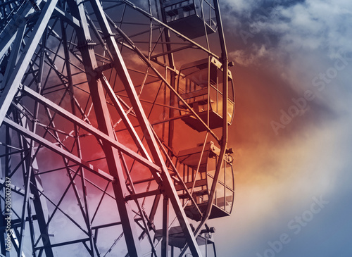 part of a Ferris wheel against a blue sky with a light