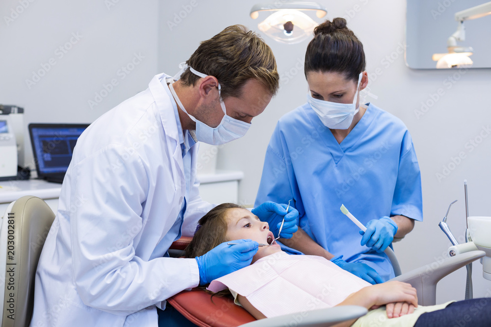 Obraz premium Dentist examining a young patient with tools 