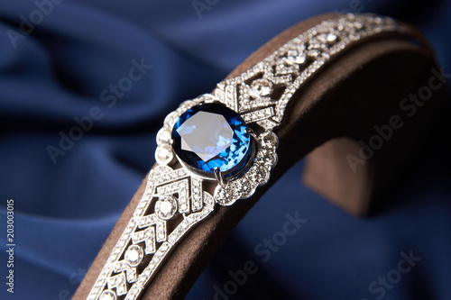 Close-up of a Beautiful platinum bracelet. Luxury women bracelet with diamonds and sapphire on blue silk background, close-up