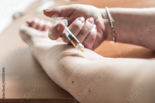 Woman puts a syringe in the arm with medicine or illegal drugs.