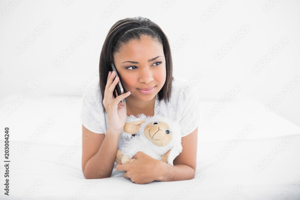 Dreamy young dark haired model making phone call while cuddling a plush sheep Dreamy young dark haired model making phone call while cuddling a plush sheep