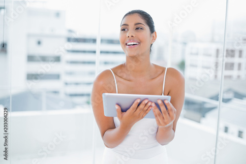 Laughing toned brunette holding tablet Free Download Laughing toned brunette holding tablet - GFXLoad