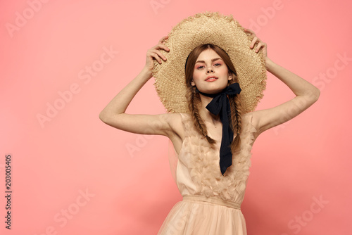 woman in a straw hat on a pink background