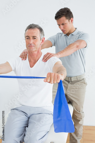 Therapist massaging mans shoulder in gym hospital