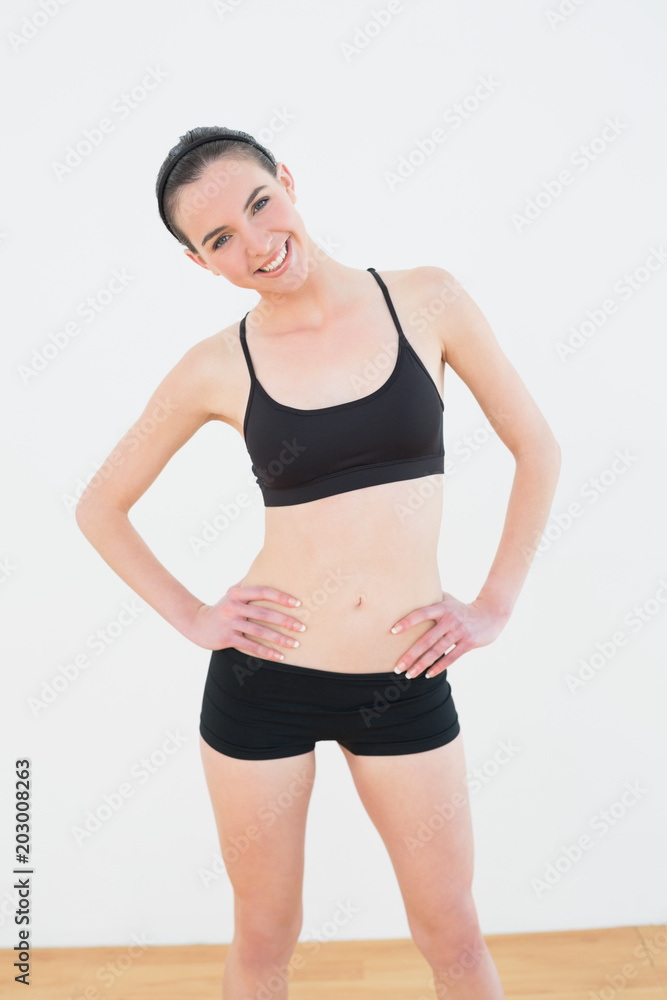 Smiling toned woman with hands on hips in fitness studio Smiling toned woman with hands on hips in fitness studio