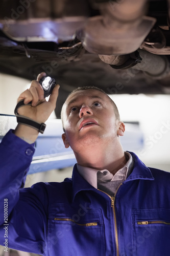 Mechanic holding a flashlight while looking at a car
