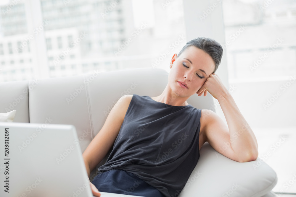 Beautiful well dressed woman resting on sofa while using laptop Beautiful well dressed woman resting on sofa while using laptop