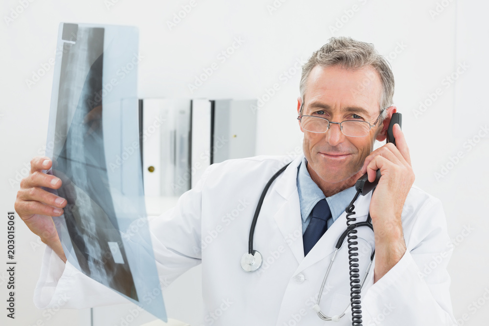 Doctor with xray picture using telephone at office Doctor with xray picture using telephone at office