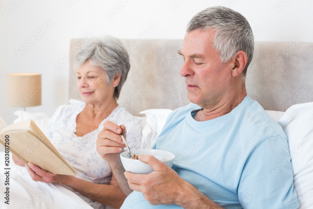 Senior couple with cereal bowl and book Senior couple with cereal bowl and book