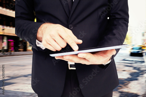 Mid section of a businessman touching digital tablet against new york street