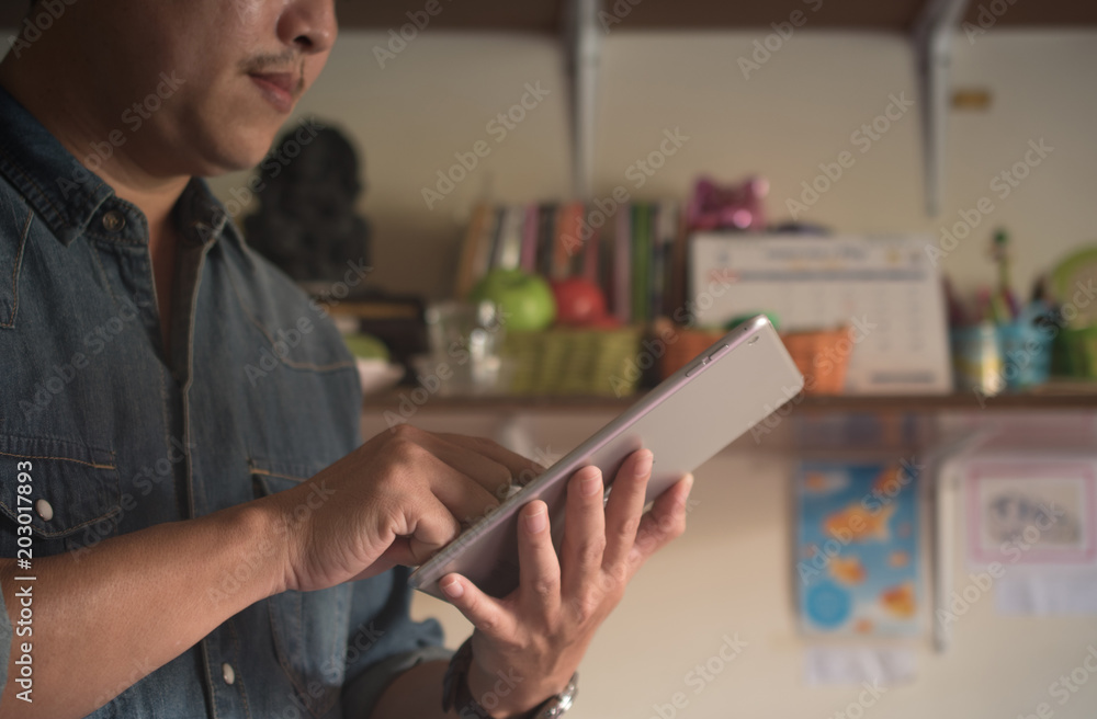 man in Jeans jecket standing on home and holding tablet computer. concept small business.