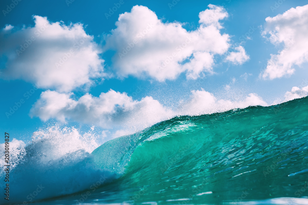 Blue wave in ocean. Breaking big wave and sky with clouds